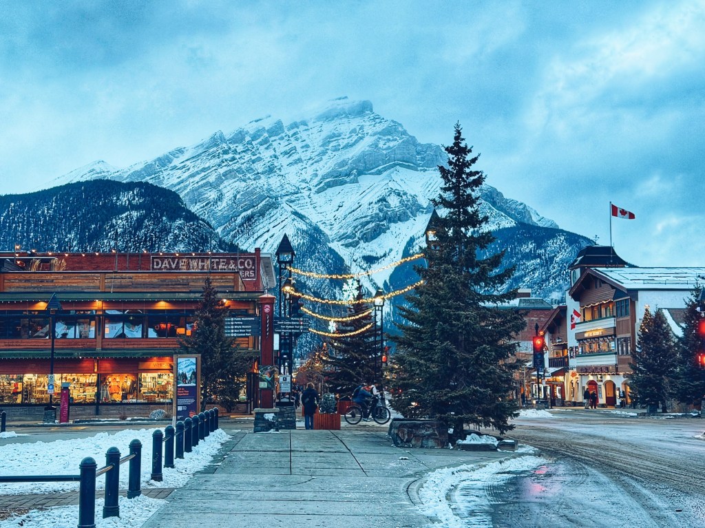 Scenic winter view of downtown Banff Avenue with shops and restaurants, framed by the snow-capped Cascade Mountain in Banff National Park